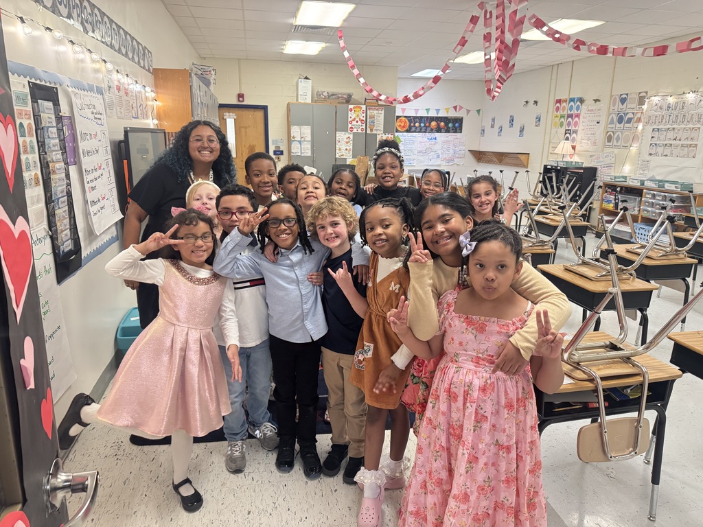 Ms. Roselle and her students smiling in the classroom before going to their concert performance