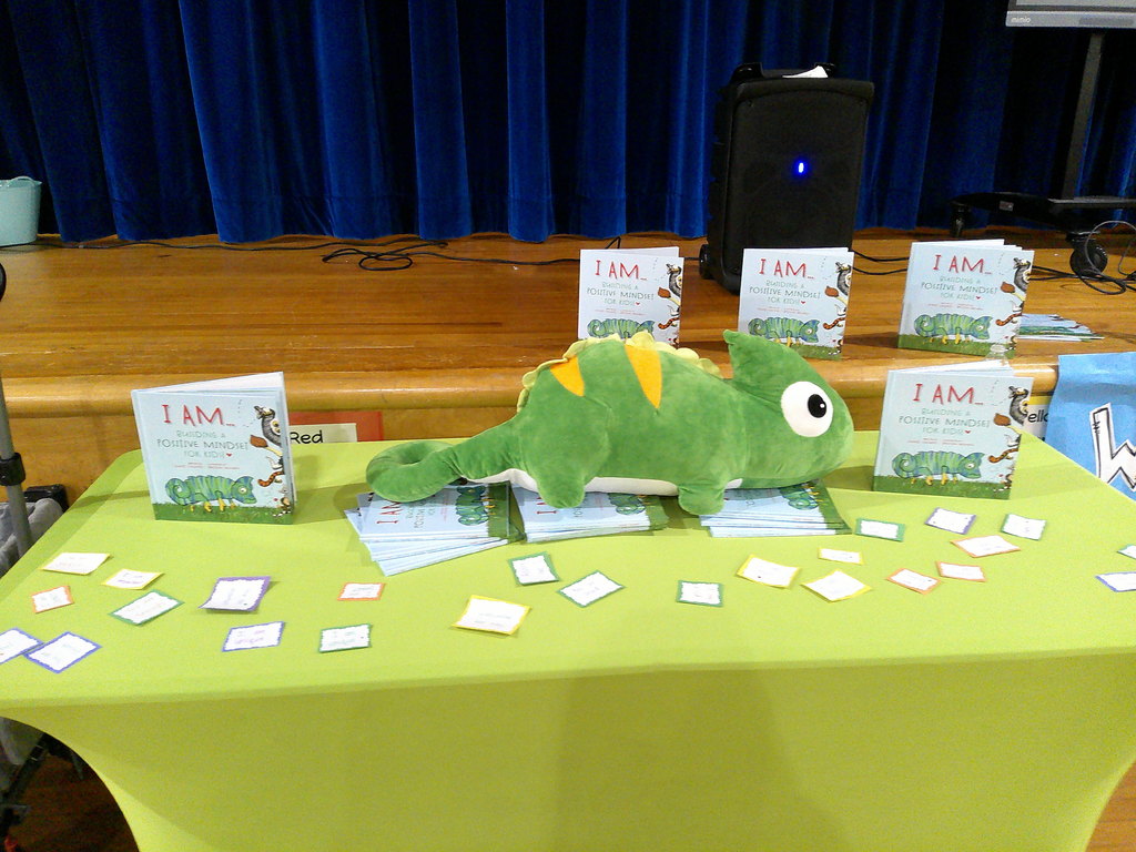 Leland Clelland's display table showing a stuffed animal chameleon and several copies of his book (I AM...Building a Positive Mindset) 