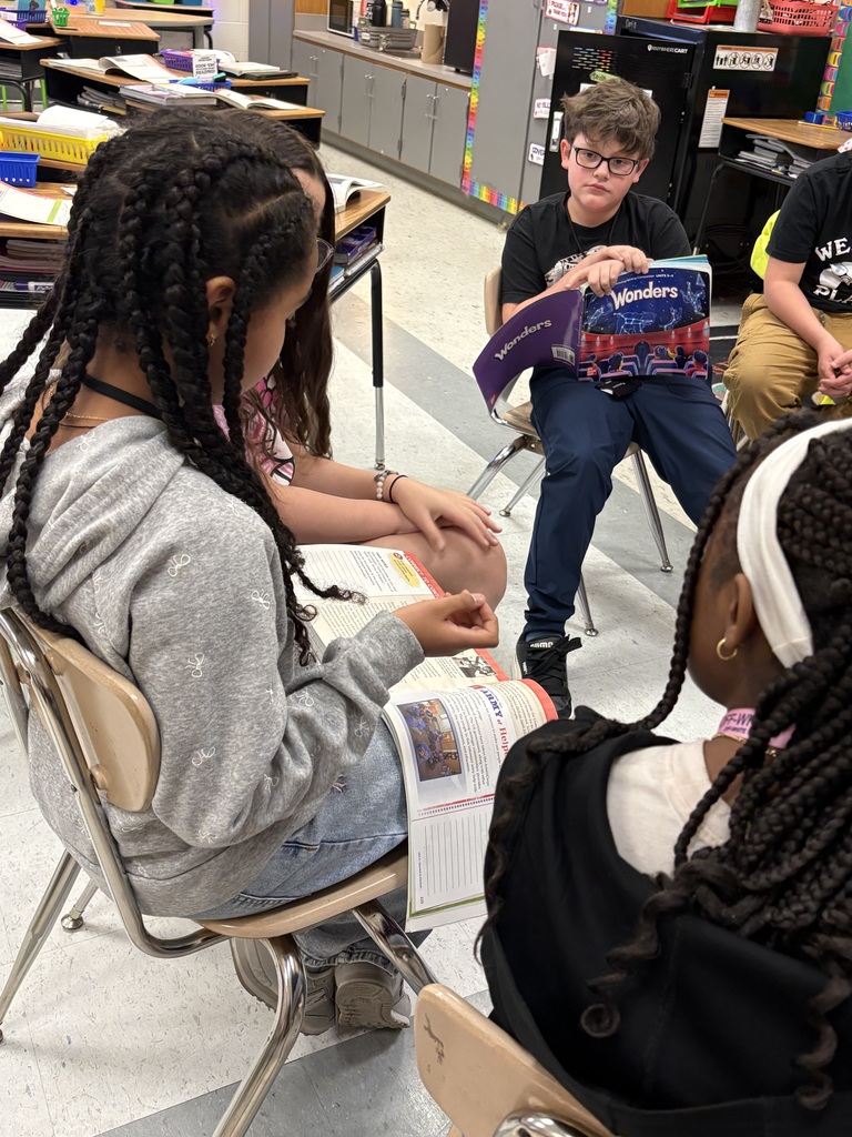 Students sitting in chairs in a circle with books