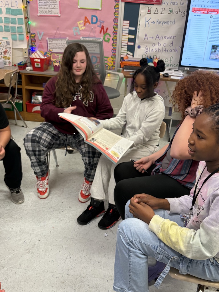 Students sitting in a circle with their books having a discussion