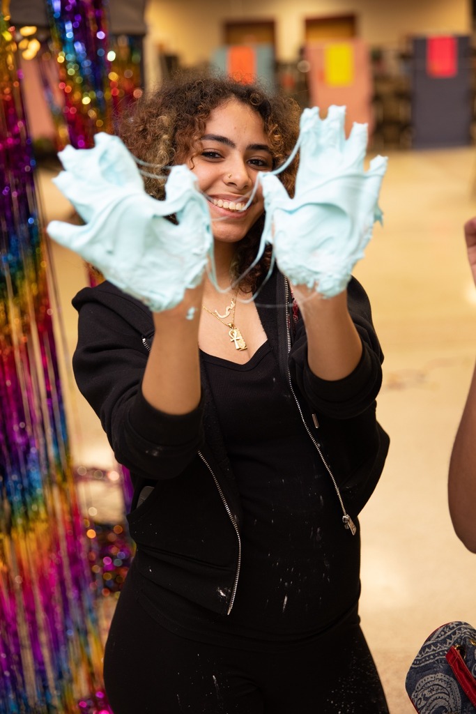 student with slime covered hands smiling