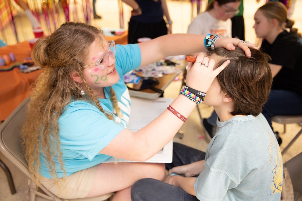 student facepainting another student