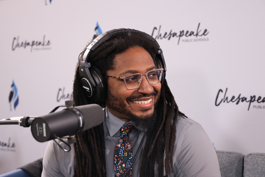 Orion smiling in the studio with a microphone and headset.
