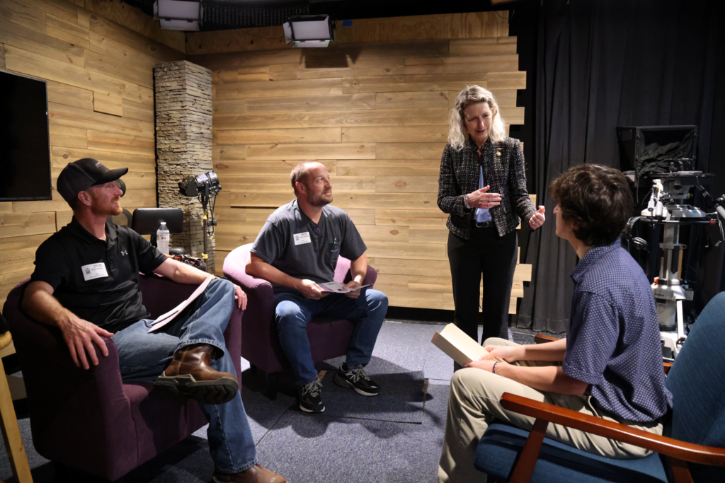 Kiggins talking to student and teacher in video production studio at CCC