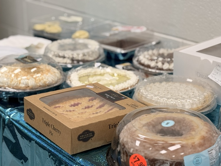 photo of table spread showing pizzas and pies