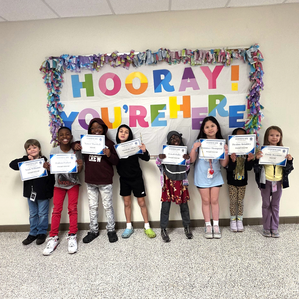3rd grade students standing together and posing to show their honor roll certificates
