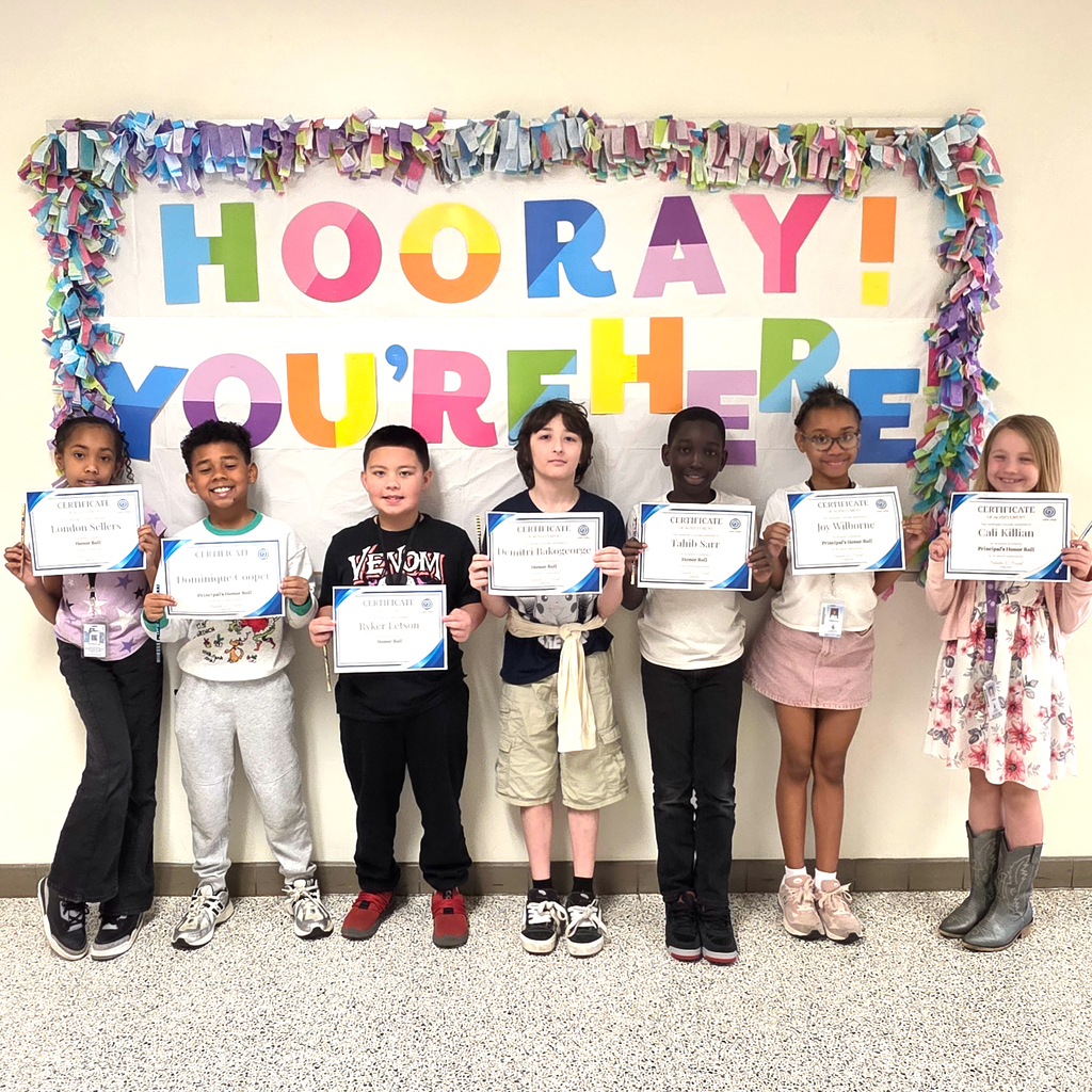 3rd grade students standing together and posing to show their honor roll certificates