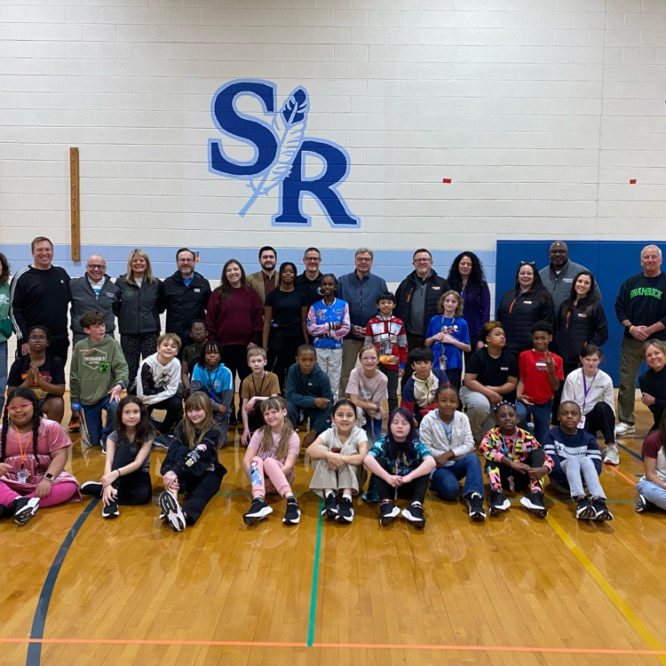 group shot with students and community proudly showing off their new sneakers. 