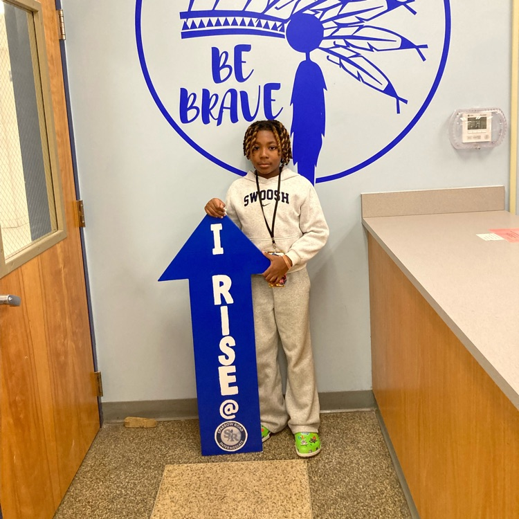 student standing by the  I RISE arrow. 