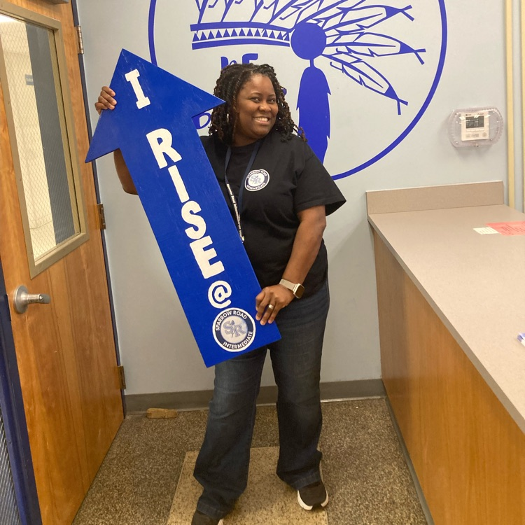 Mrs. Young proudly holding the I RISE arrow. 