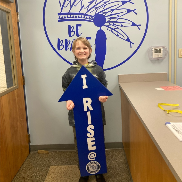 Student proudly holding I RISE arrow. 