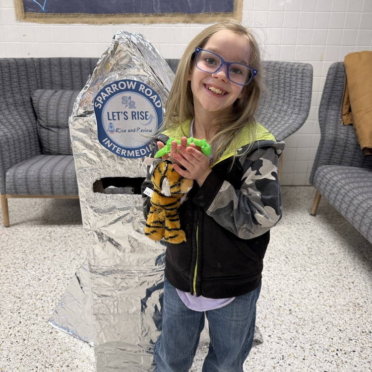 Student proudly standing by the RISE and Review Rocket.