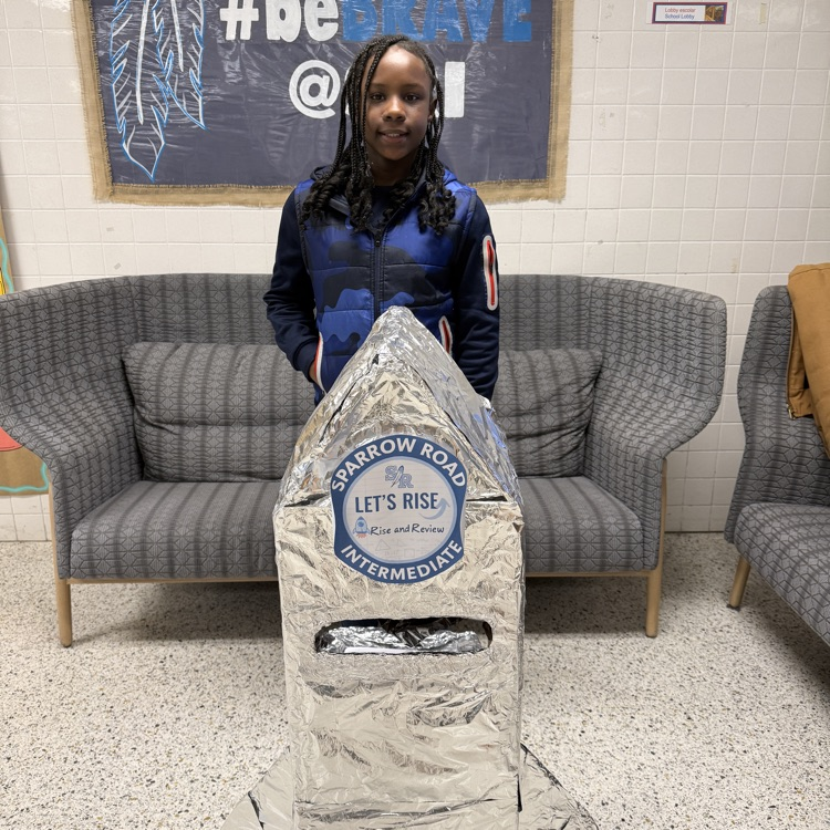 Student proudly standing by the RISE and Review Rocket.