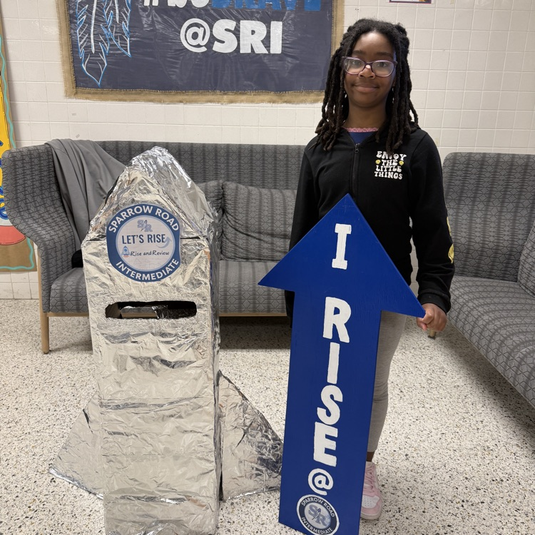 Student proudly standing by the RISE and Review Rocket.