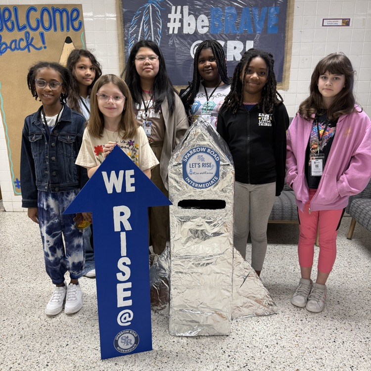 Students proudly standing by the RISE and Review Rocket.