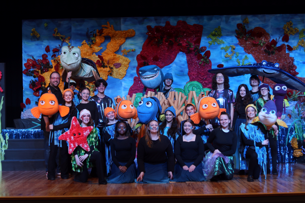 happy excited students on stage celebrating their performance with puppets