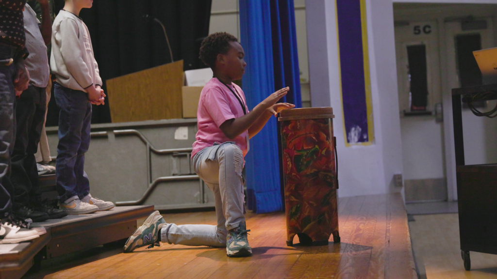 student focused on drumming his bongo