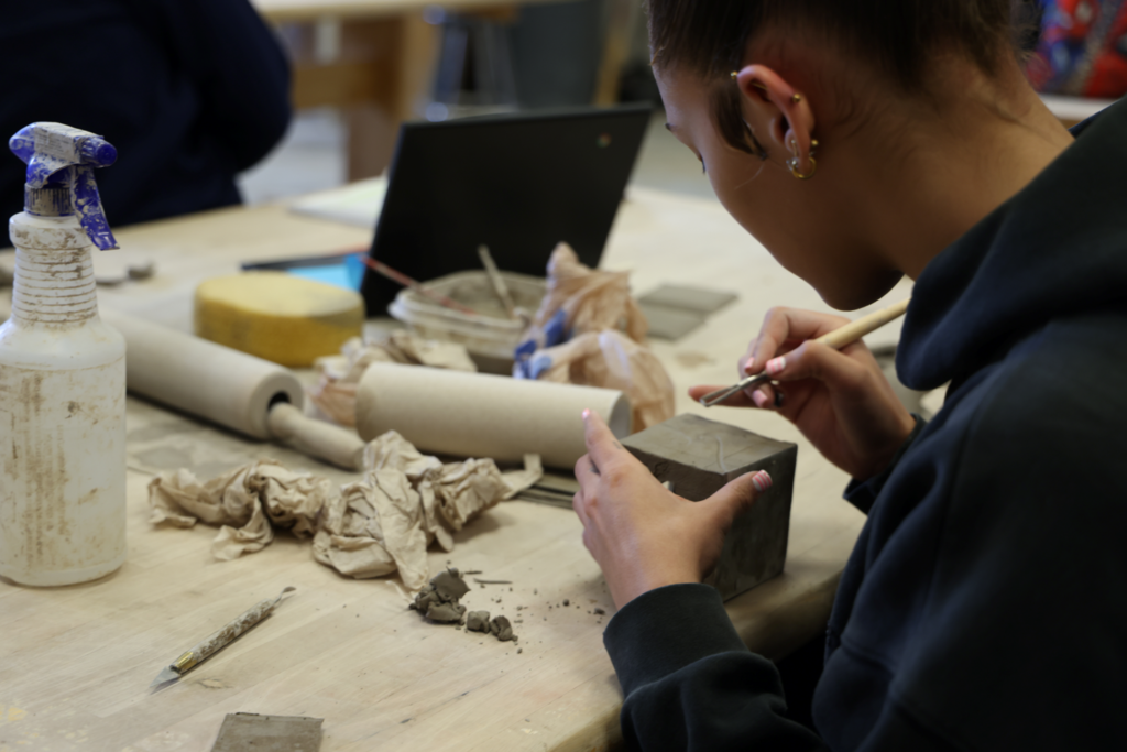 student concentrating on comleting her ceramics piece