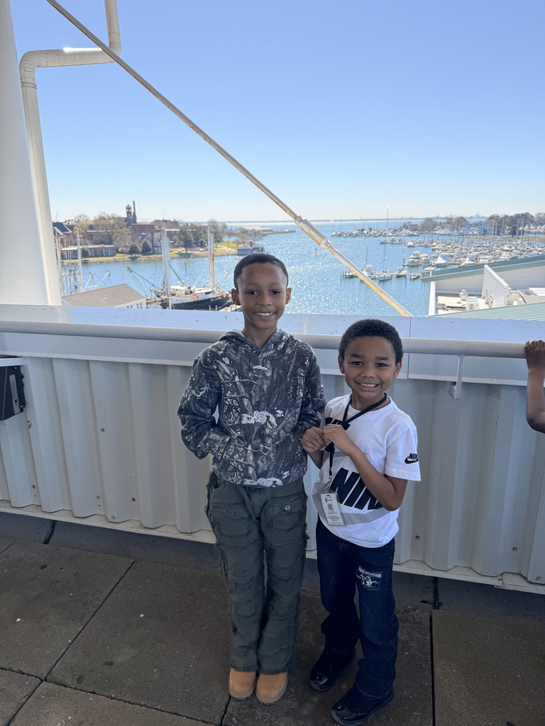 two students pose on a ship with a marina in the background