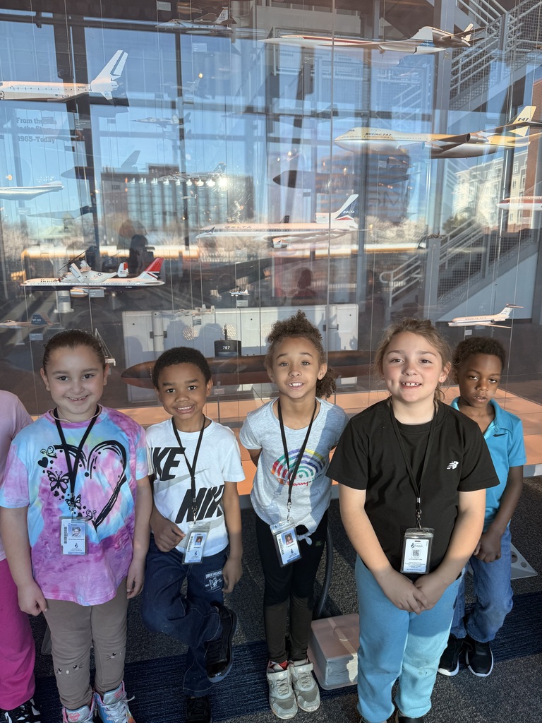 students pose in front of airplane models