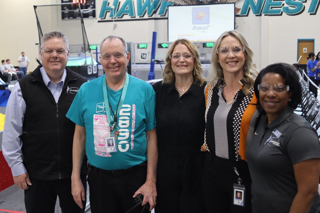 Teacher Richard Douglas and district leaders smiling together at the competition.