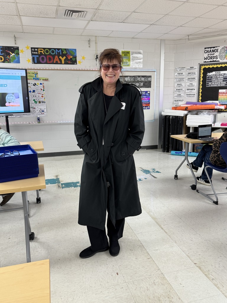 A teacher dressed in a long trench coat as a secret agent