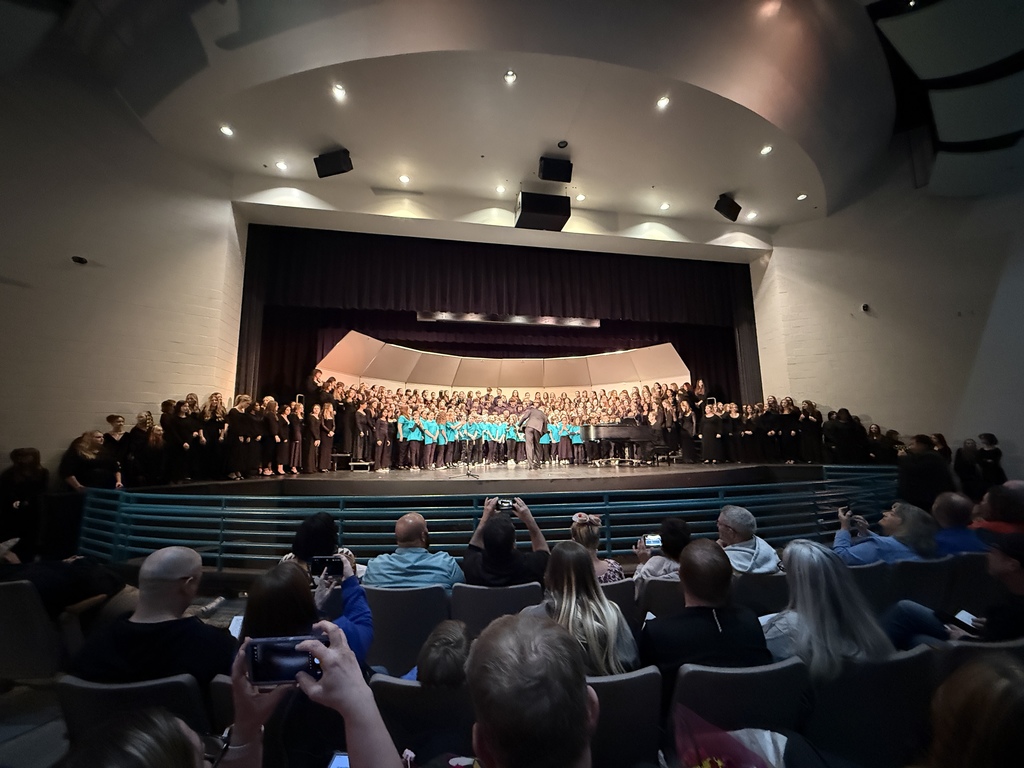choral students on stage as proud parents watch on and capture the moment on phones