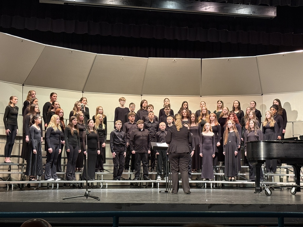 choral students on stage performing with choral director in front