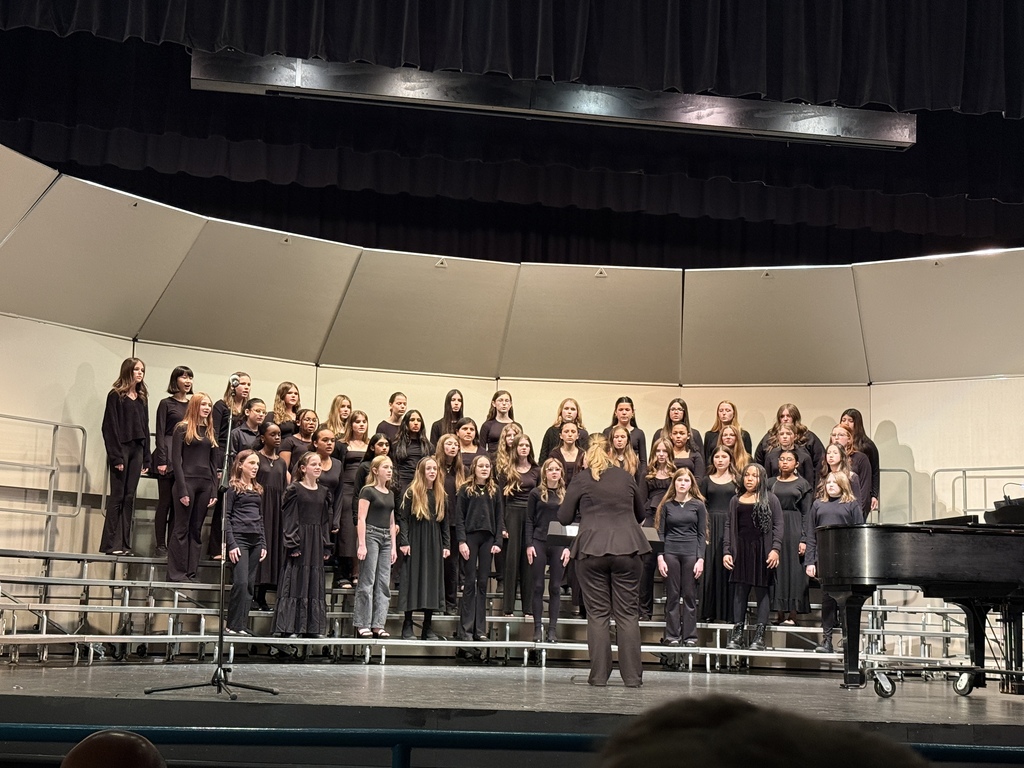 choral students on stage performing with choral director in front
