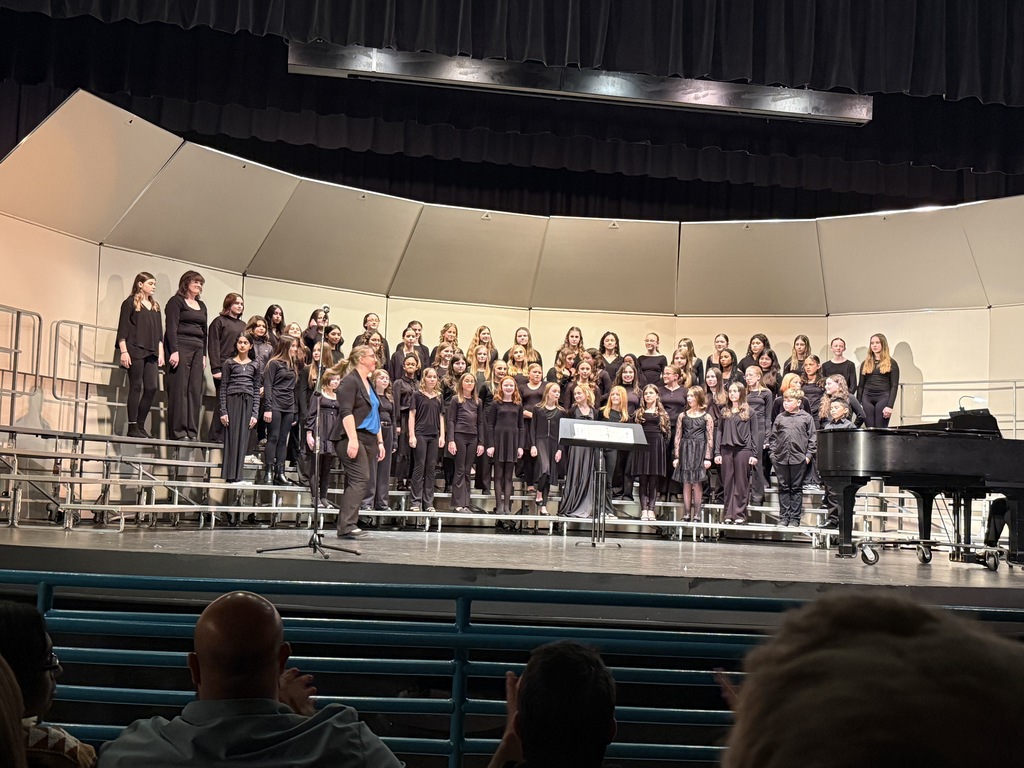 choral students on stage performing with choral director in front