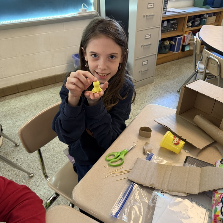 Student proudly showing off clay model.