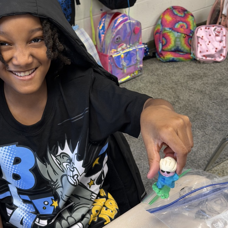 Student proudly showing off their clay figure.