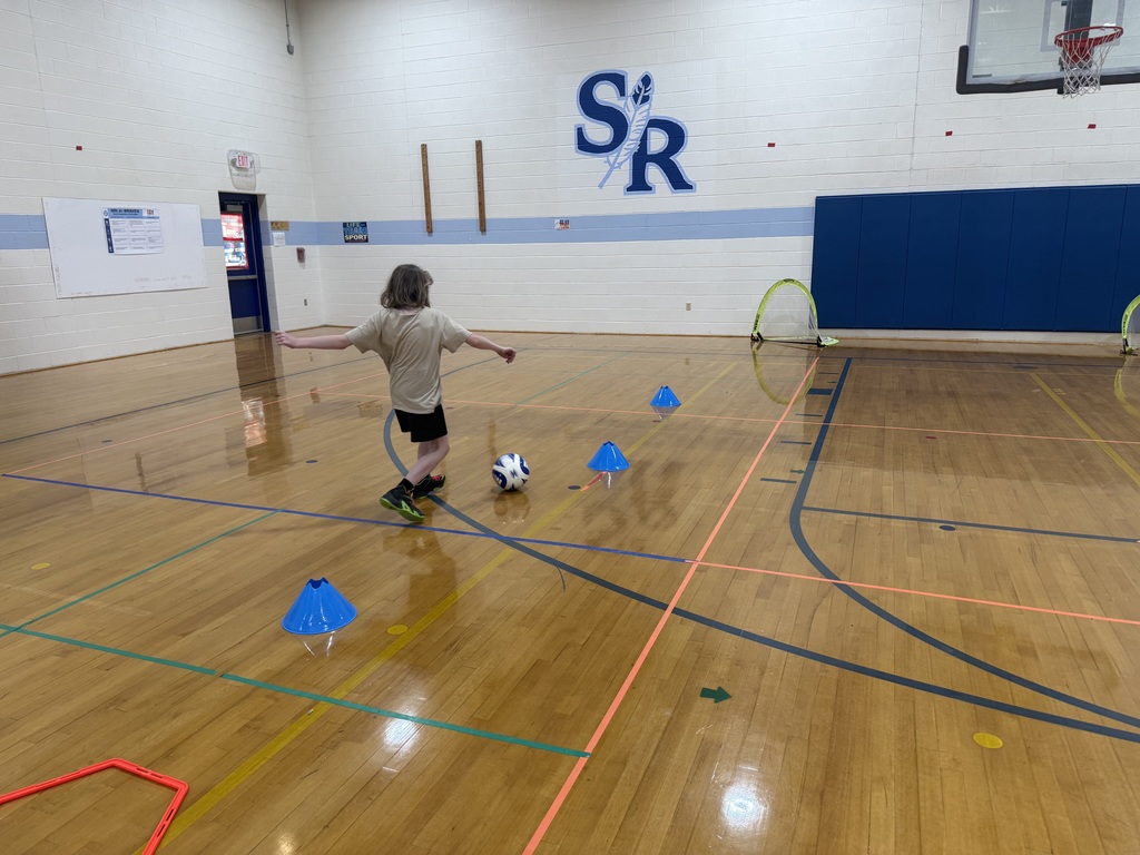 Student running with soccer ball around cones to score a goal!