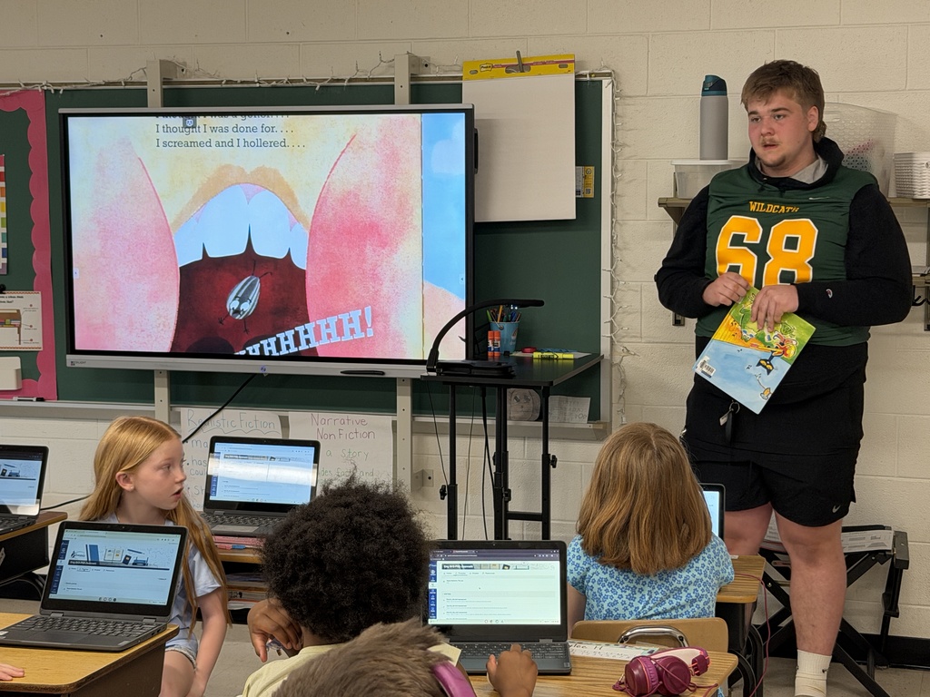 Football player reading to class and answering questions.
