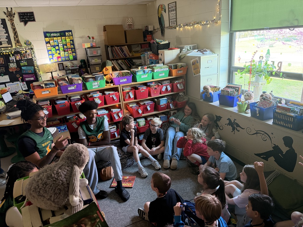 Football player reading to class in the reading center.