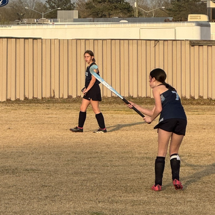 girls playing field hockey