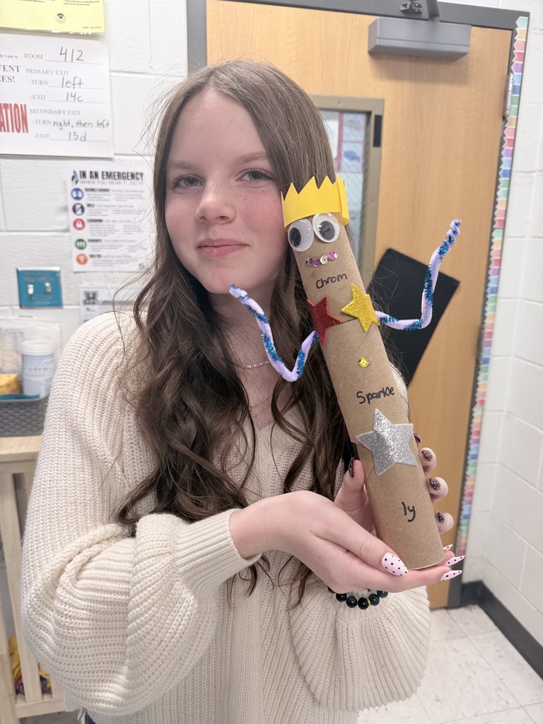 student proudly posing with the hand crafted creature