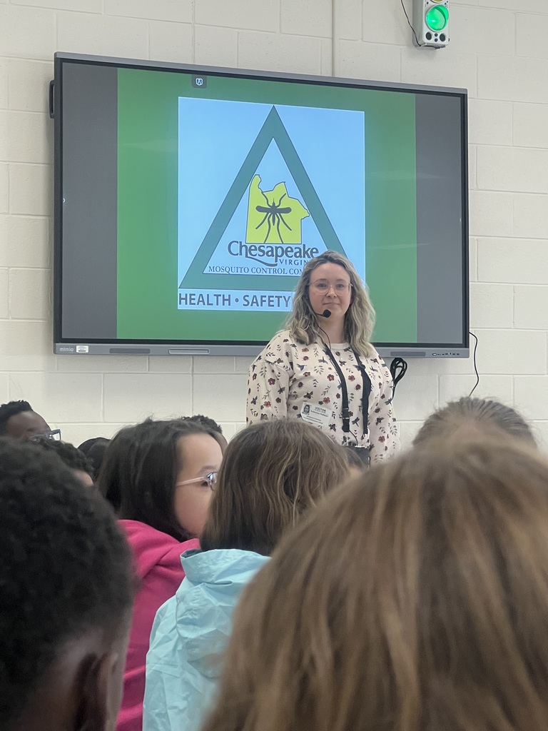 A presenter stands in front of a large screen showing the Chesapeake Mosquito Control logo, addressing a group of attentive third-grade students.