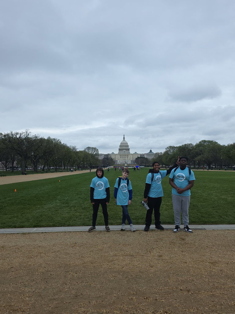 A group of 8th grade students smiling and posing together on the Memorial.