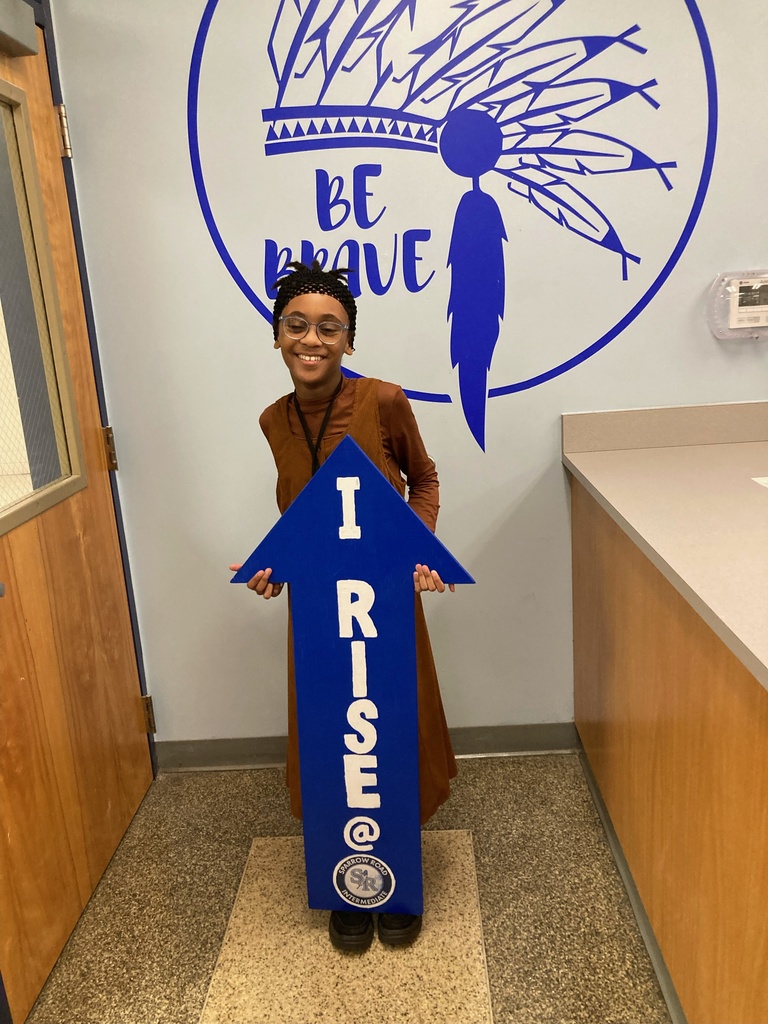 Student proudly holding up the I RISE arrow. 
