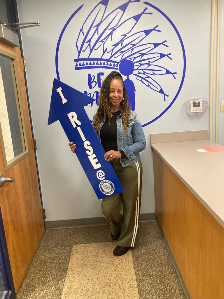 Teacher proudly holding up the I RISE arrow. 