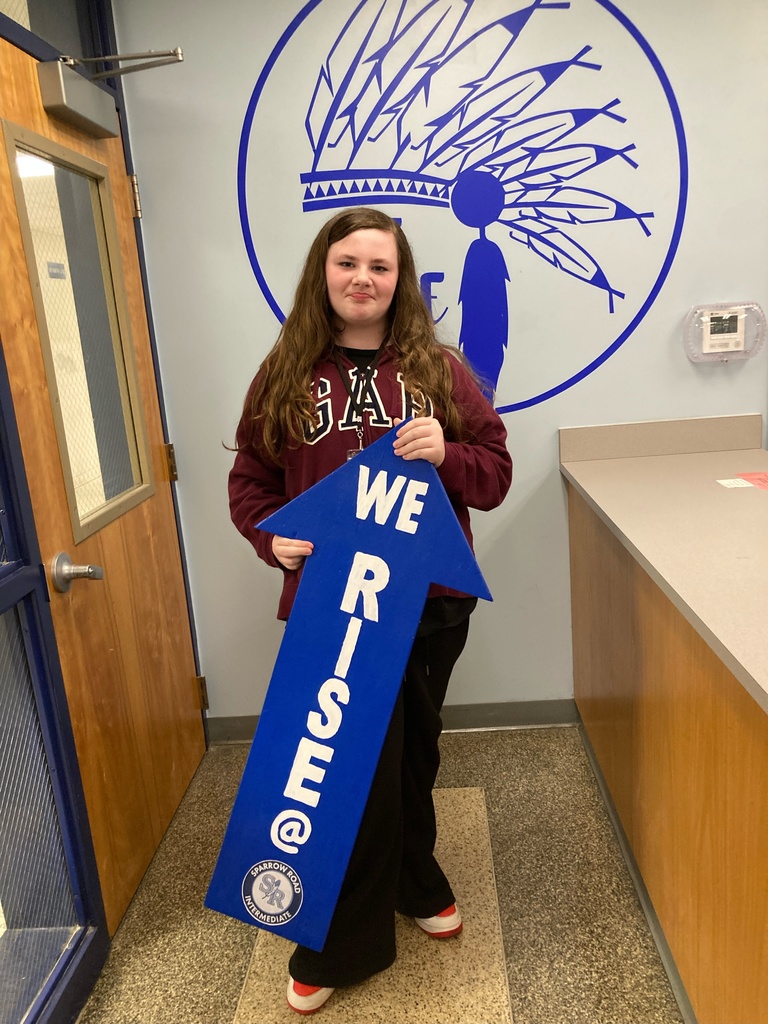 Student proudly holding up the I RISE arrow. 