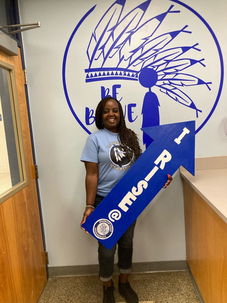 Teacher proudly holding up the I RISE arrow. 