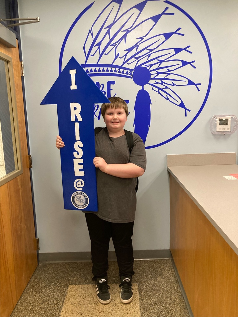 Student proudly holding up the I RISE arrow. 