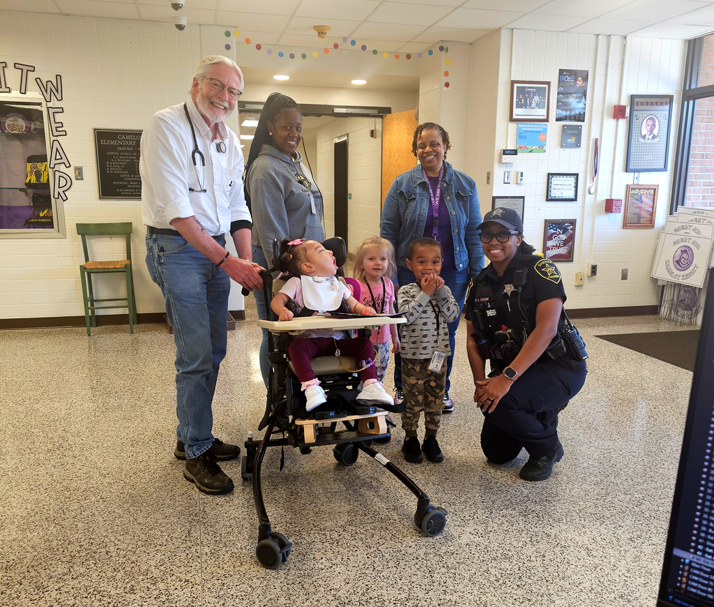 sheriff kneeling next a few preschool students and their teachers