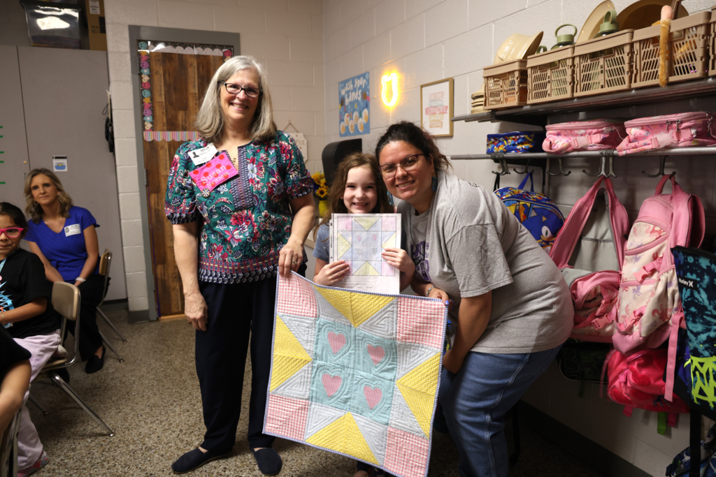 student is excited to receive an original quilt made for her inspired by her drawing
