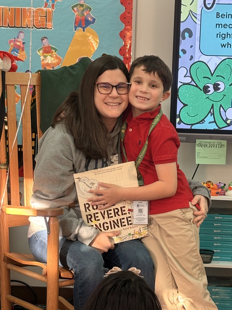A student smiles while posing with their parent after a guest reader visit in Ms. Shinn’s class.