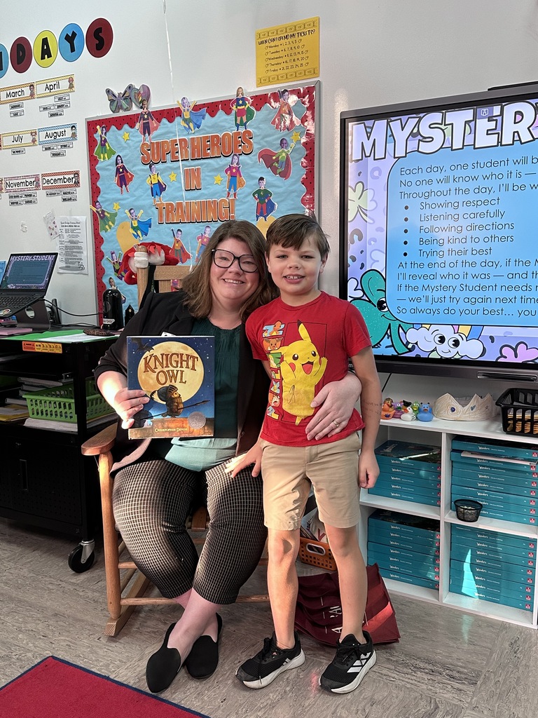 A student stands with their parent, who visited as a guest reader, in 2nd grade.