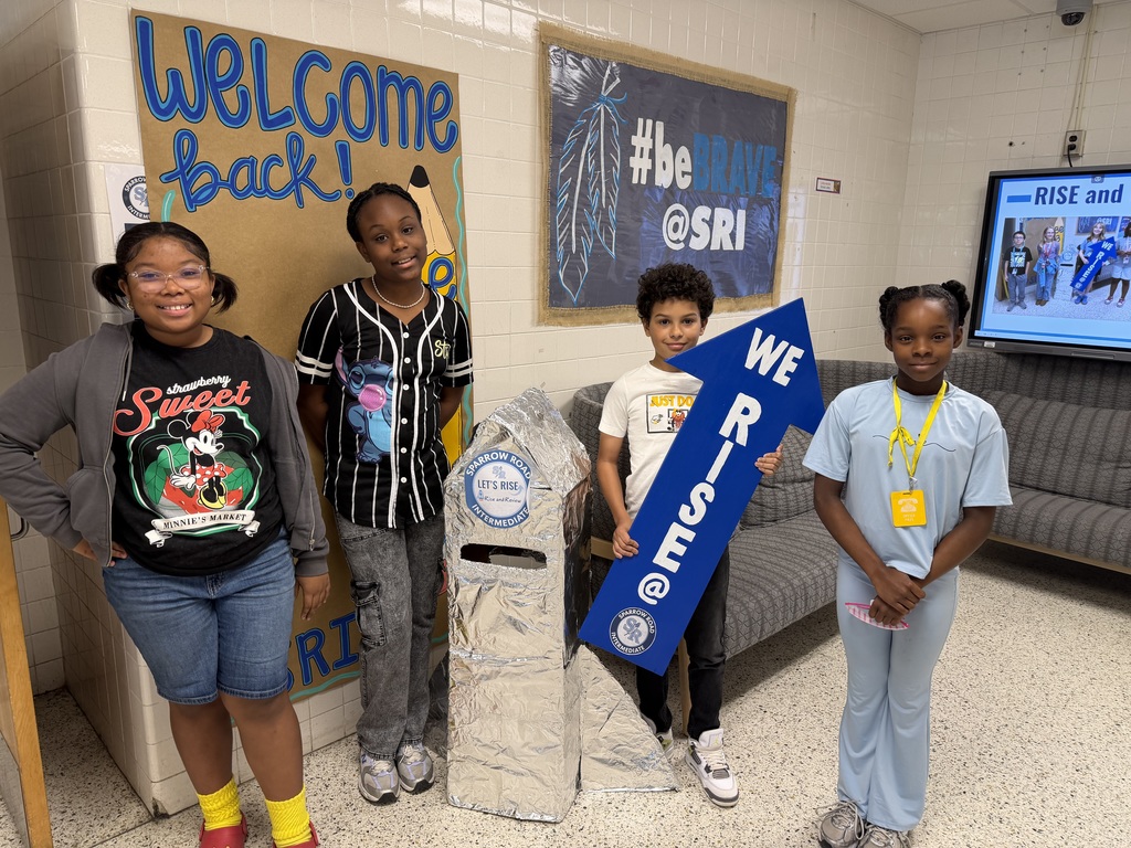 Students proudly standing by the RISE and Review rocket with the We RISE arrow.