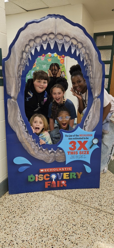 Students inside of a megalodon jaw pretending to be scared to prompt the upcoming BookFair.